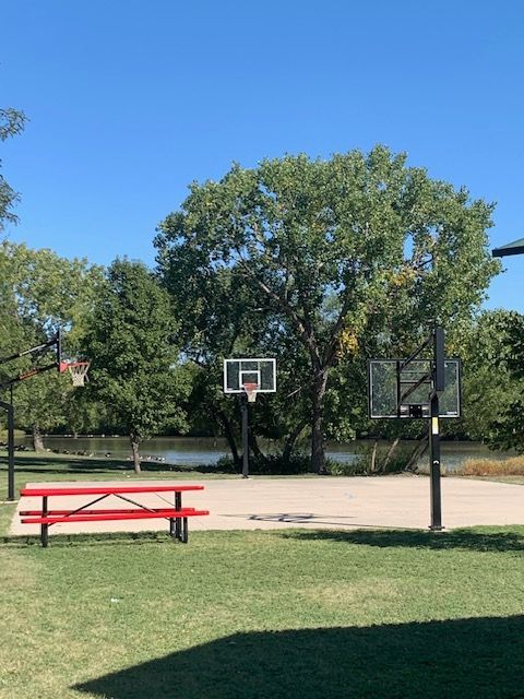 A basketball court in a park with a red picnic table