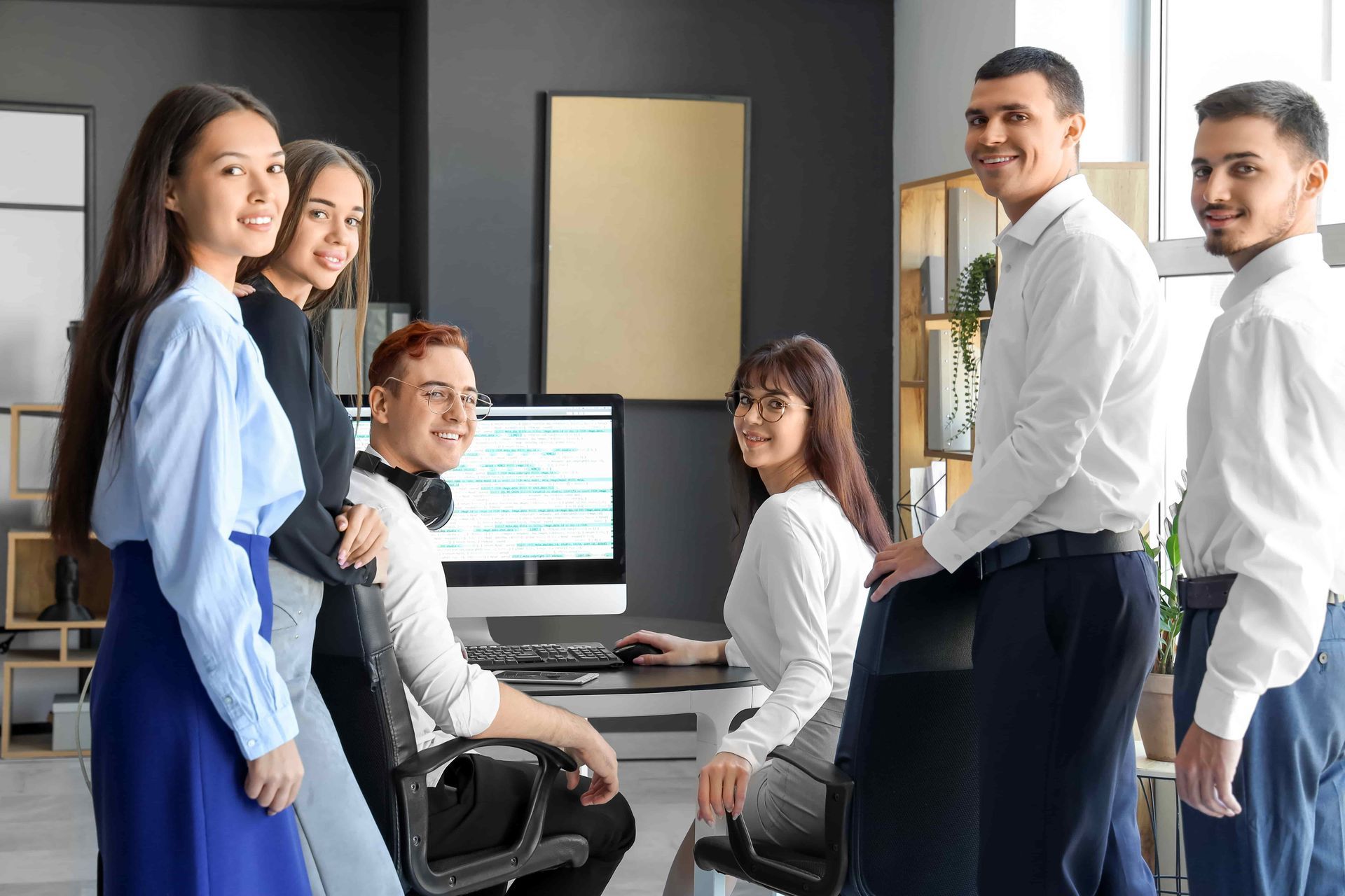 A group of people are standing next to each other in an office.