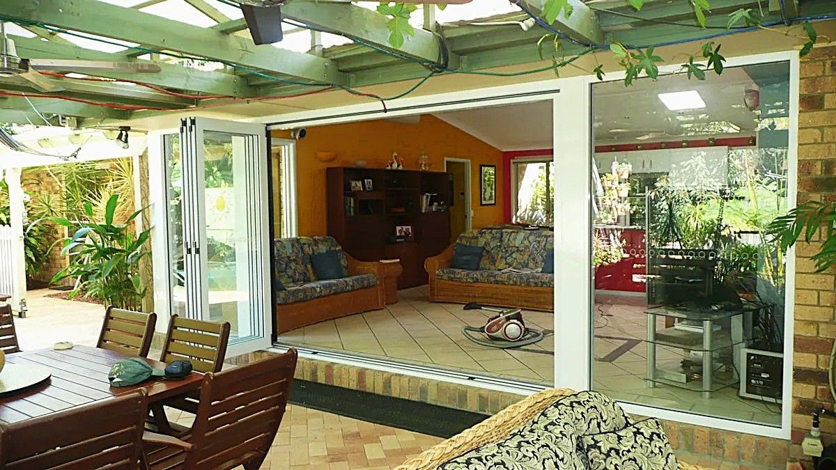 Modern aluminium bi-fold doors opening from a living area to an outdoor entertaining space in Noosa