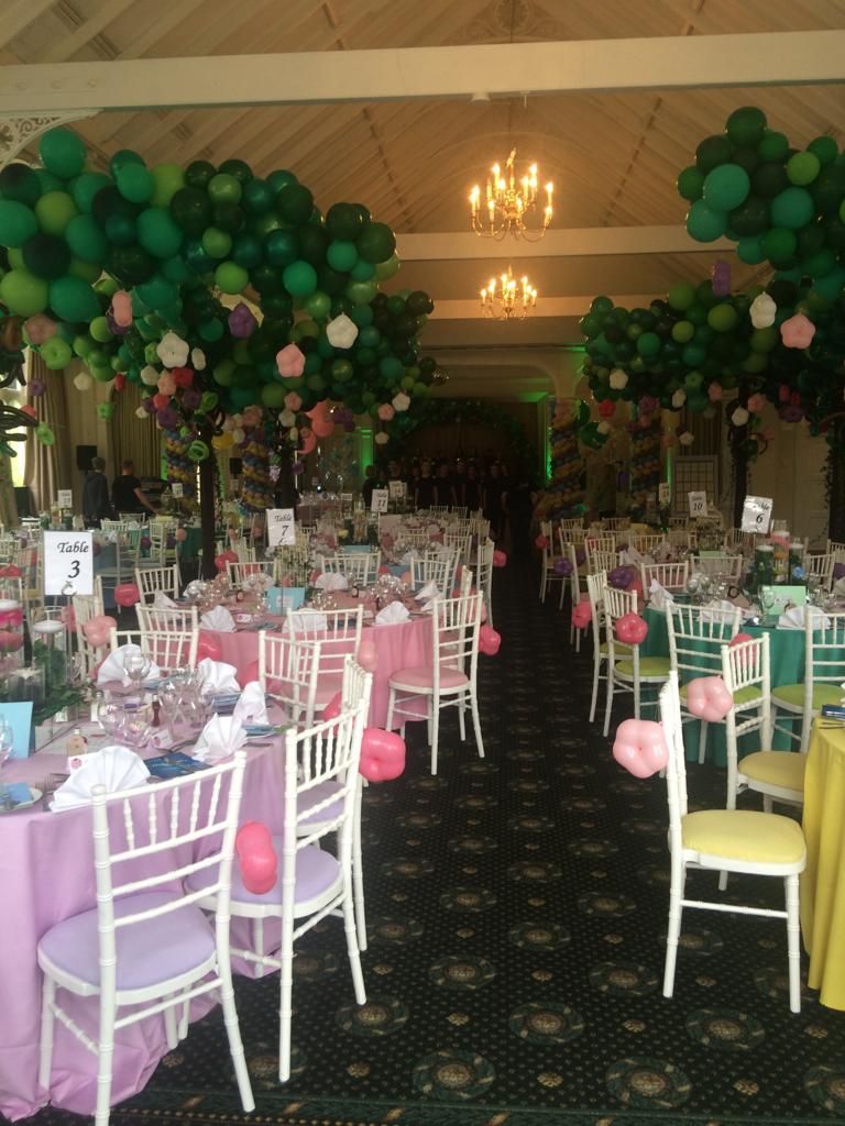A large room with tables and chairs and balloons hanging from the ceiling ready for a Friends of Alfie Martin charity event