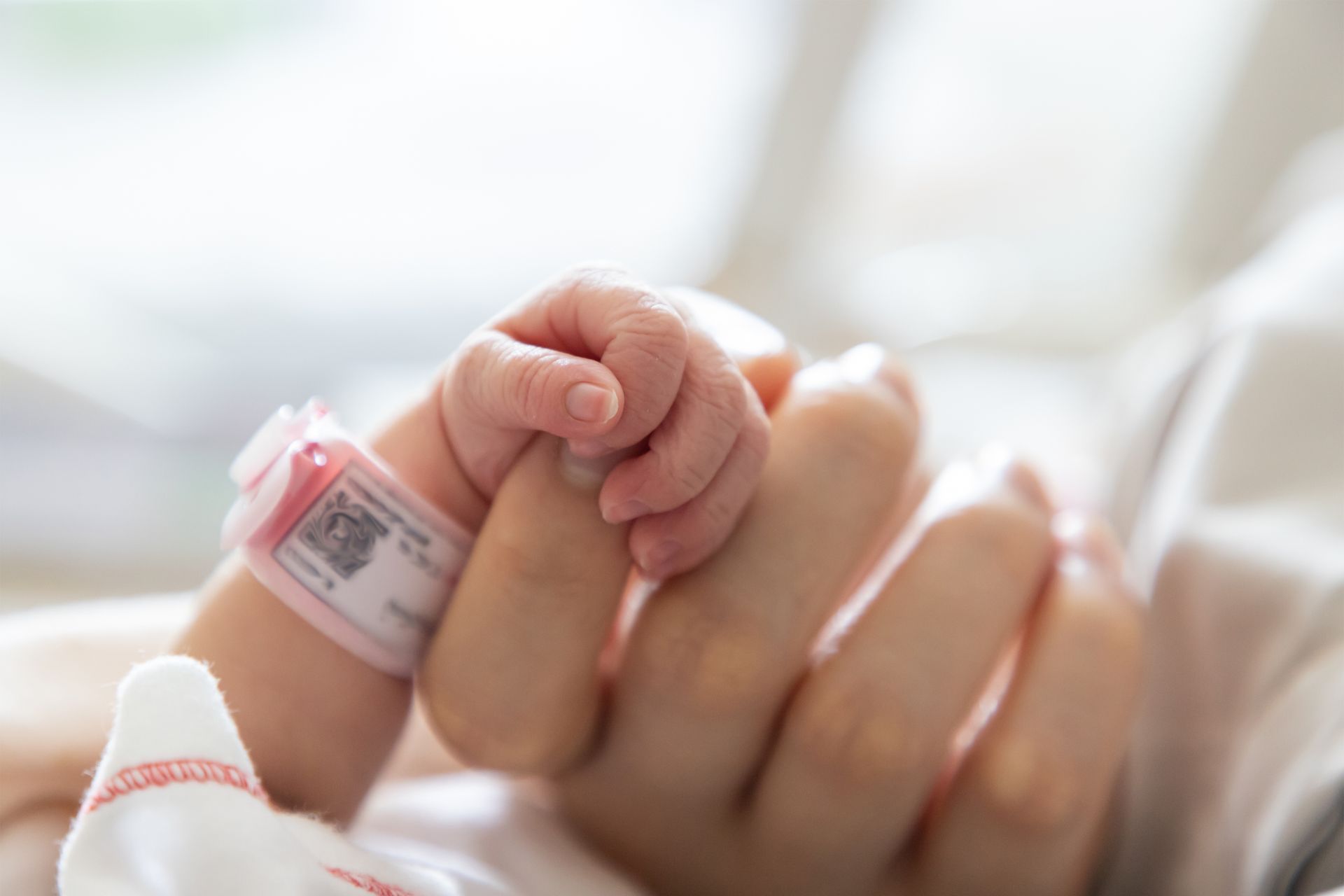 A woman is holding a baby 's hand in a hospital bed.  Friends of Alfie Martin