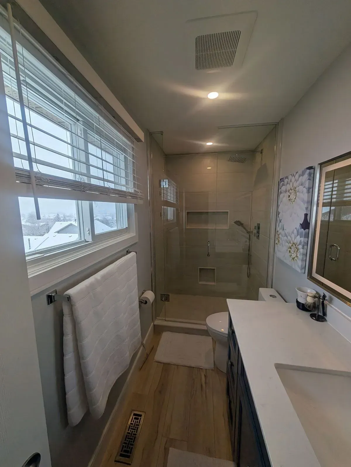 Modern ensuite with navy blue shaker vanity, quartz countertop, backlit LED mirror and frameless glass walk in shower, Hamilton Ontario