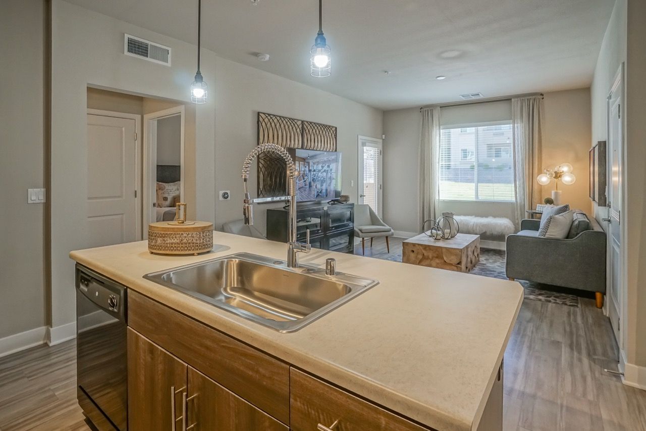 Open-concept kitchen and living room in an apartment with a large island sink and modern appliances.