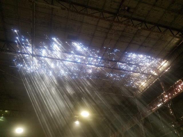 Sunlight streams through holes in a large warehouse roof.
