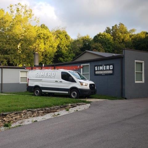 White service van parked outside a gray building with
