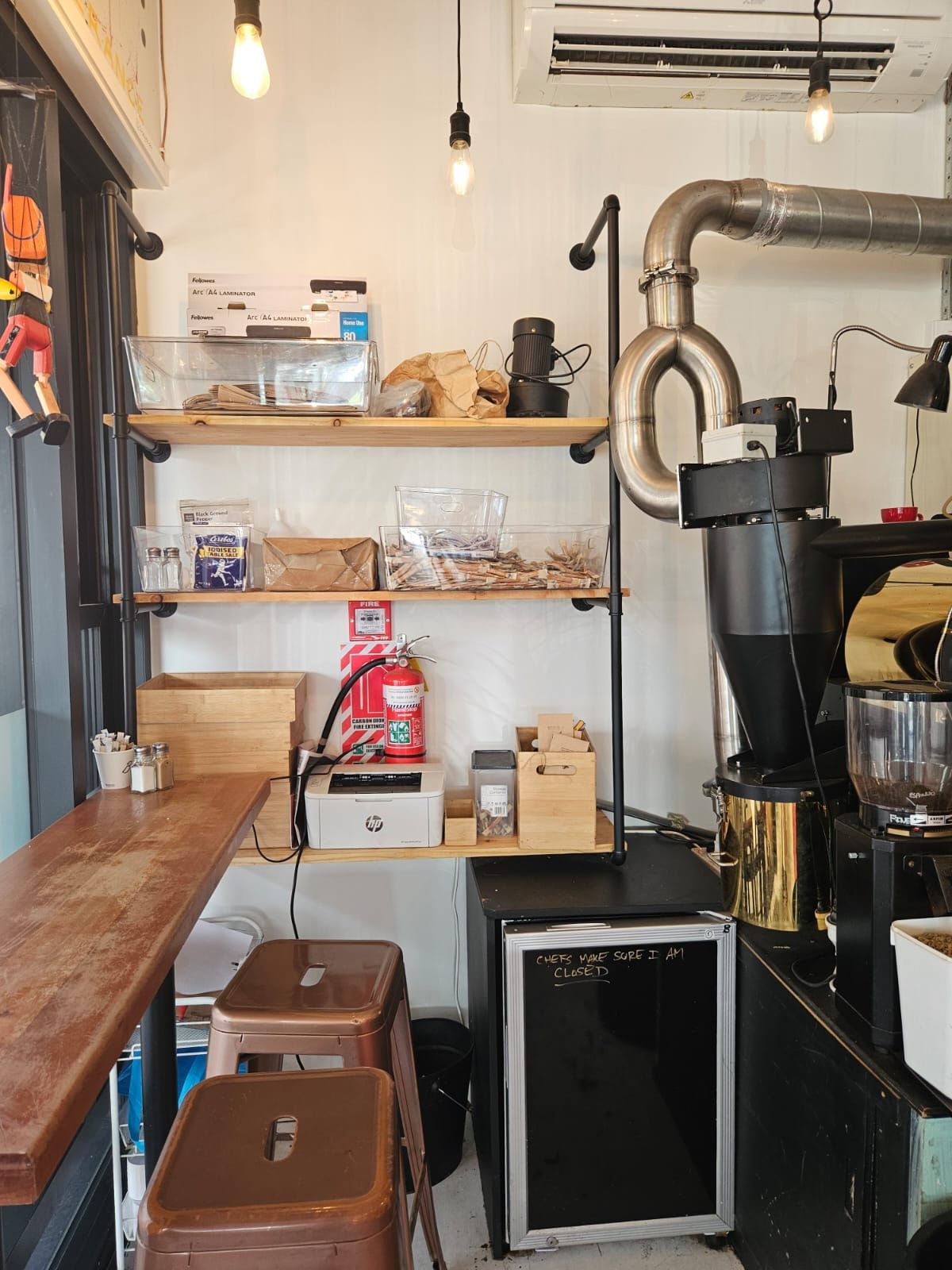 Coffee shop counter with espresso machine, grinder, and decorative hanging lights.