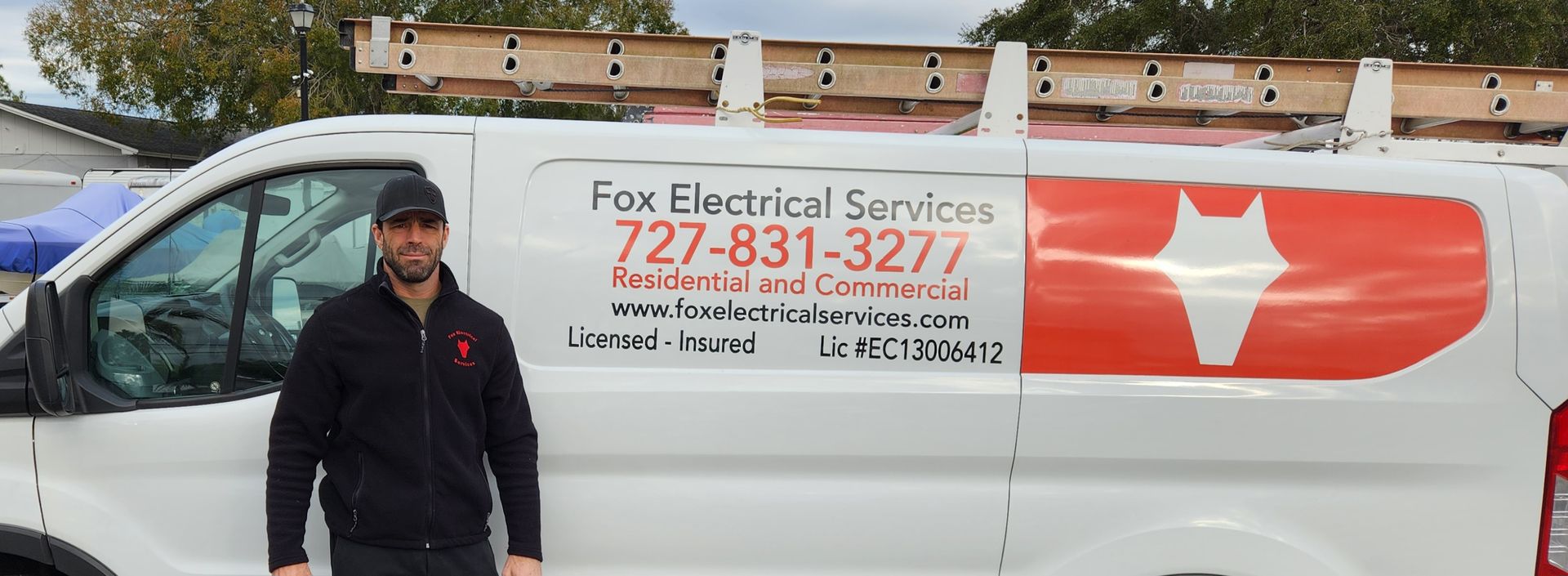 Man standing beside a white van with the Fox Electrical Services logo, red and white color scheme.