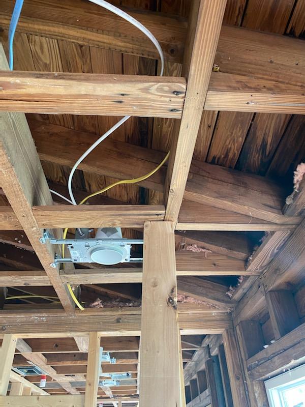 Wooden ceiling with electrical wiring and a mounted light fixture.