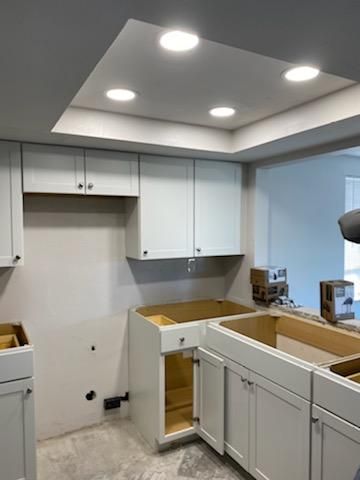 Kitchen under construction with white cabinets, recessed lighting, and bare countertops.