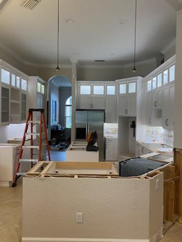 Kitchen under renovation, with white cabinets, a ladder, and construction materials.