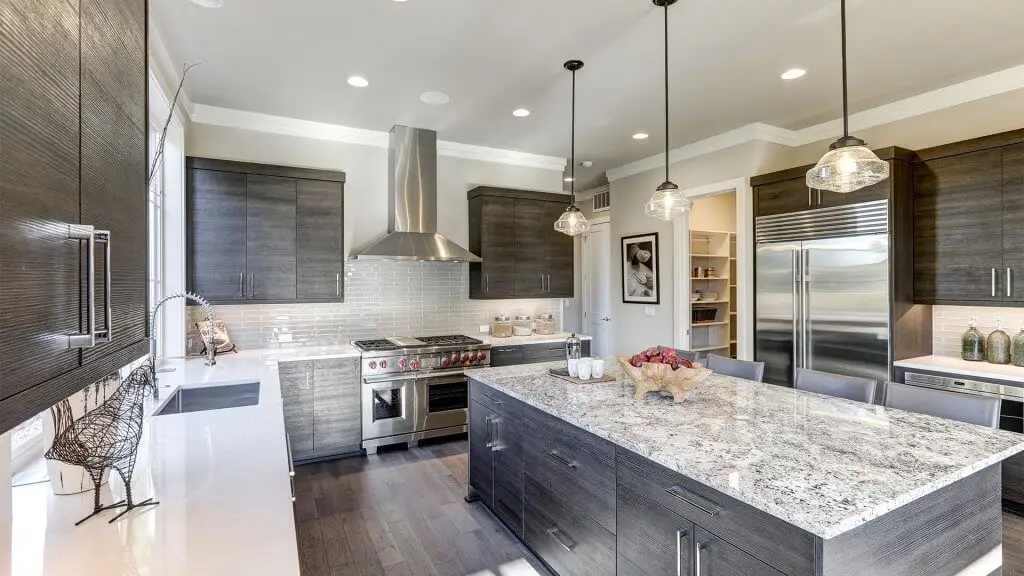 Modern kitchen with dark cabinets, stainless steel appliances, and a large island with granite countertop.