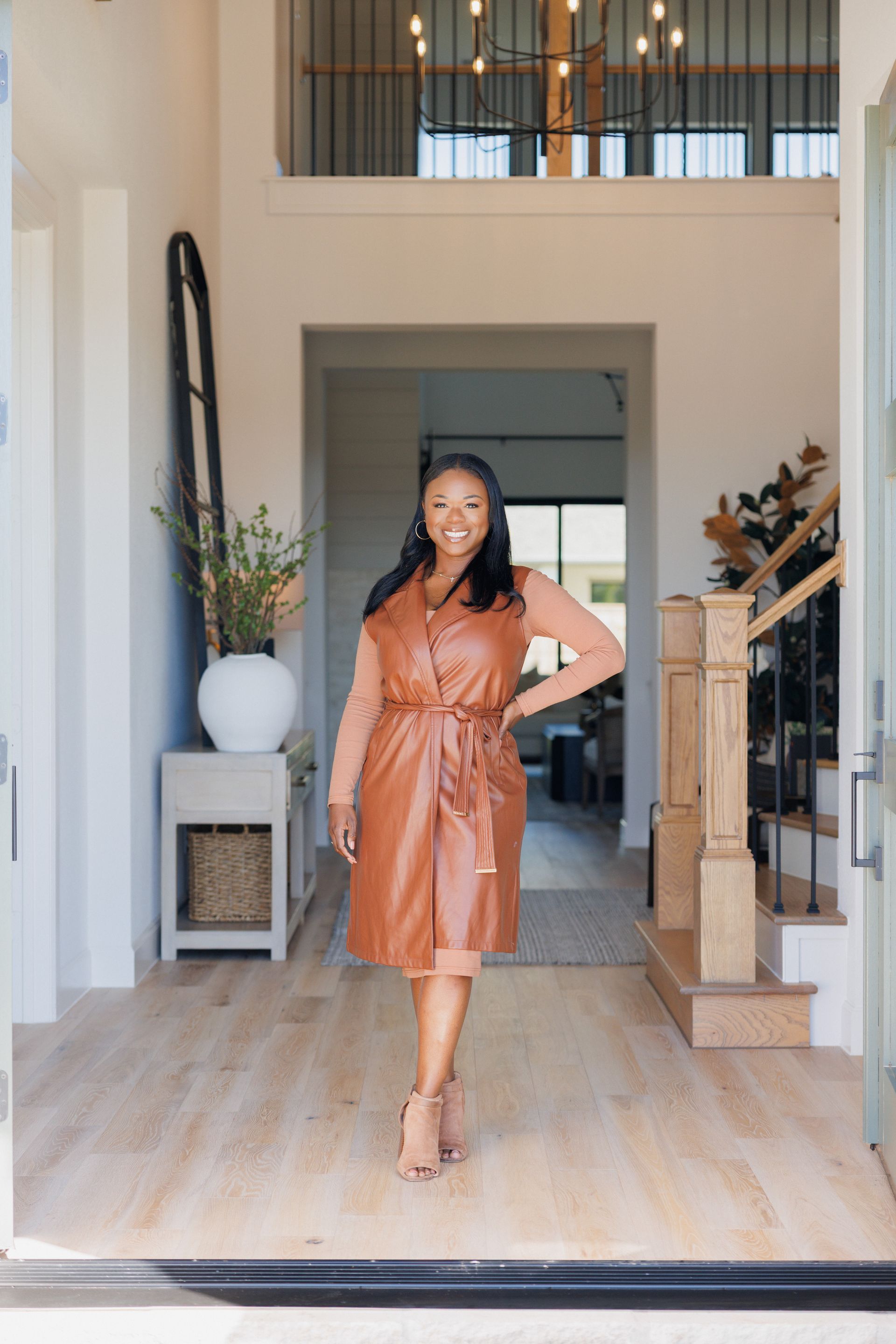 A smart and stylish realtor sitting at a desk with a laptop and a vase of flowers.