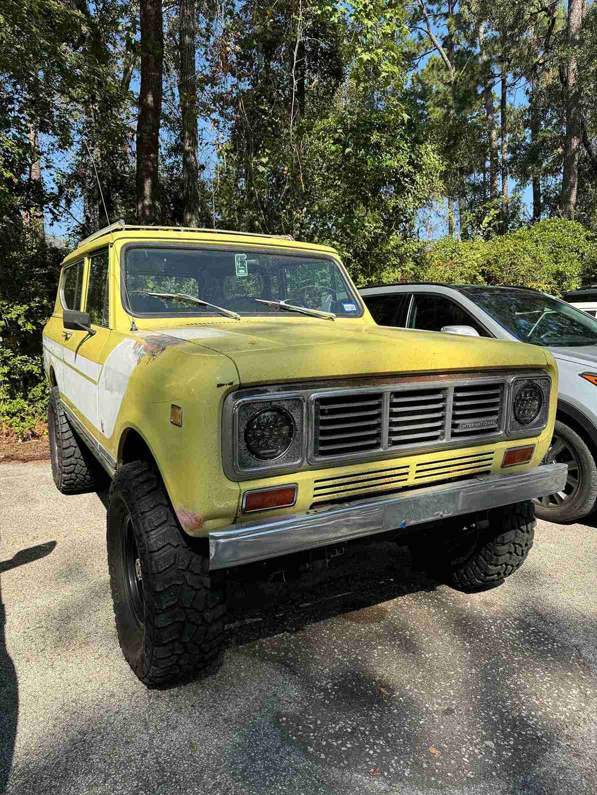Yellow vintage pickup truck parked outdoors on a sunny street, front view.