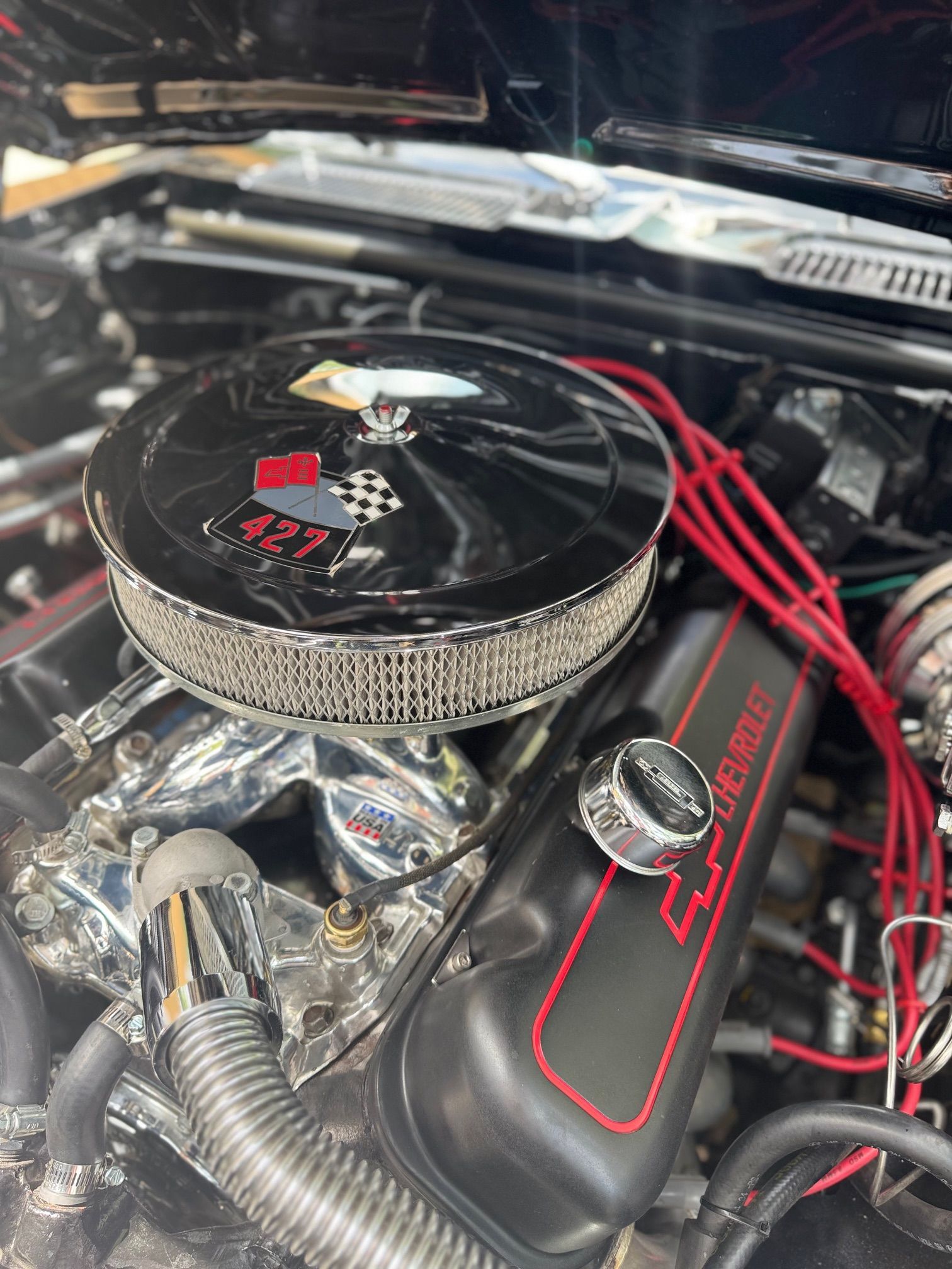 Chrome car engine with black air filter, red spark plug wires, and black valve cover with red accents