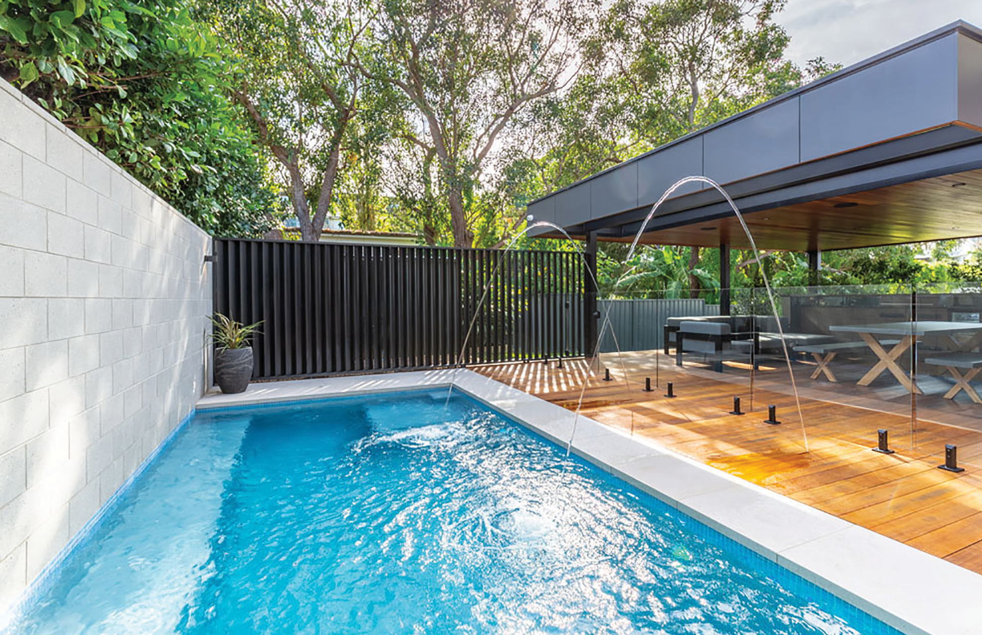 There is a large swimming pool in the backyard of a house.