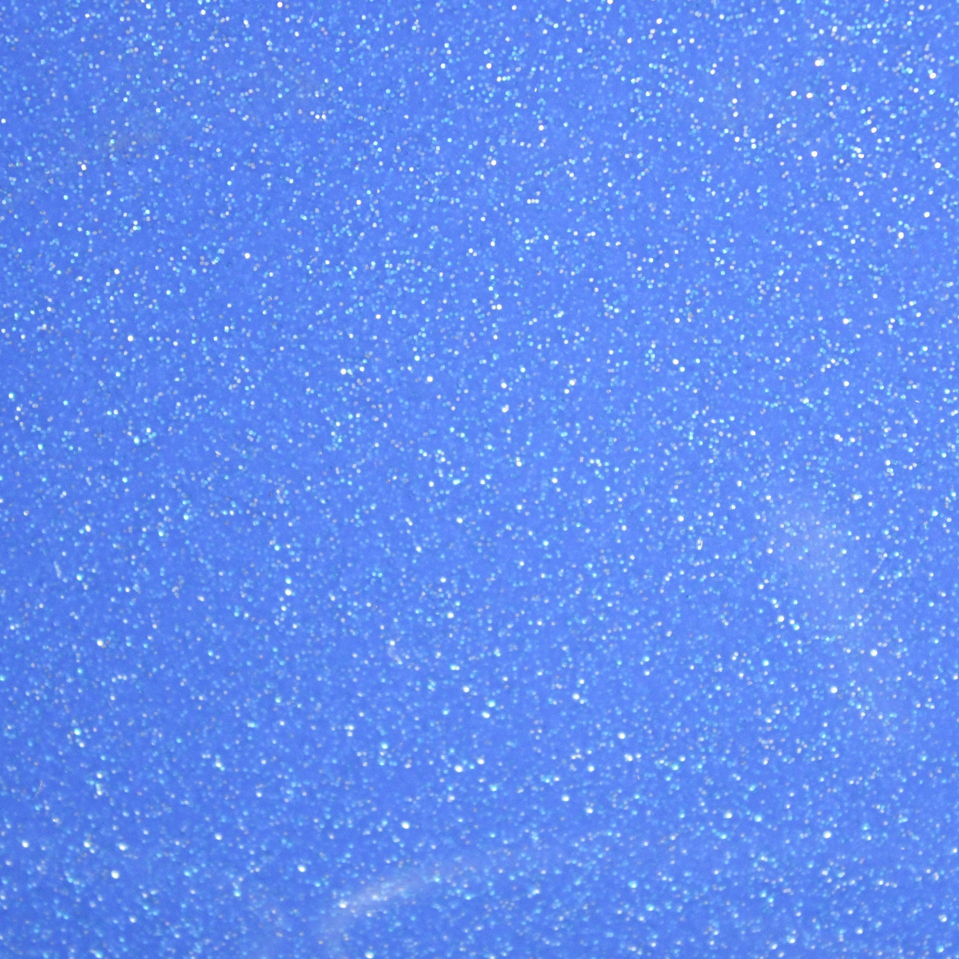 Blue glittery textured surface with scattered white specks and a faint bright streak near the bottom