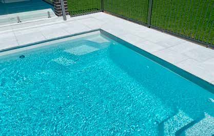 A swimming pool with stairs leading to it and a fence surrounding it.