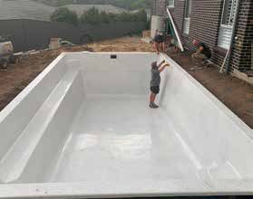 A boy is standing in the middle of a large white swimming pool.