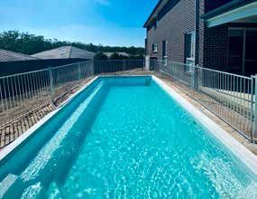 A large swimming pool surrounded by a fence in front of a house.