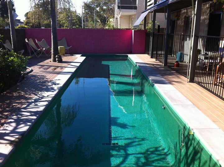 A swimming pool with a pink wall behind it