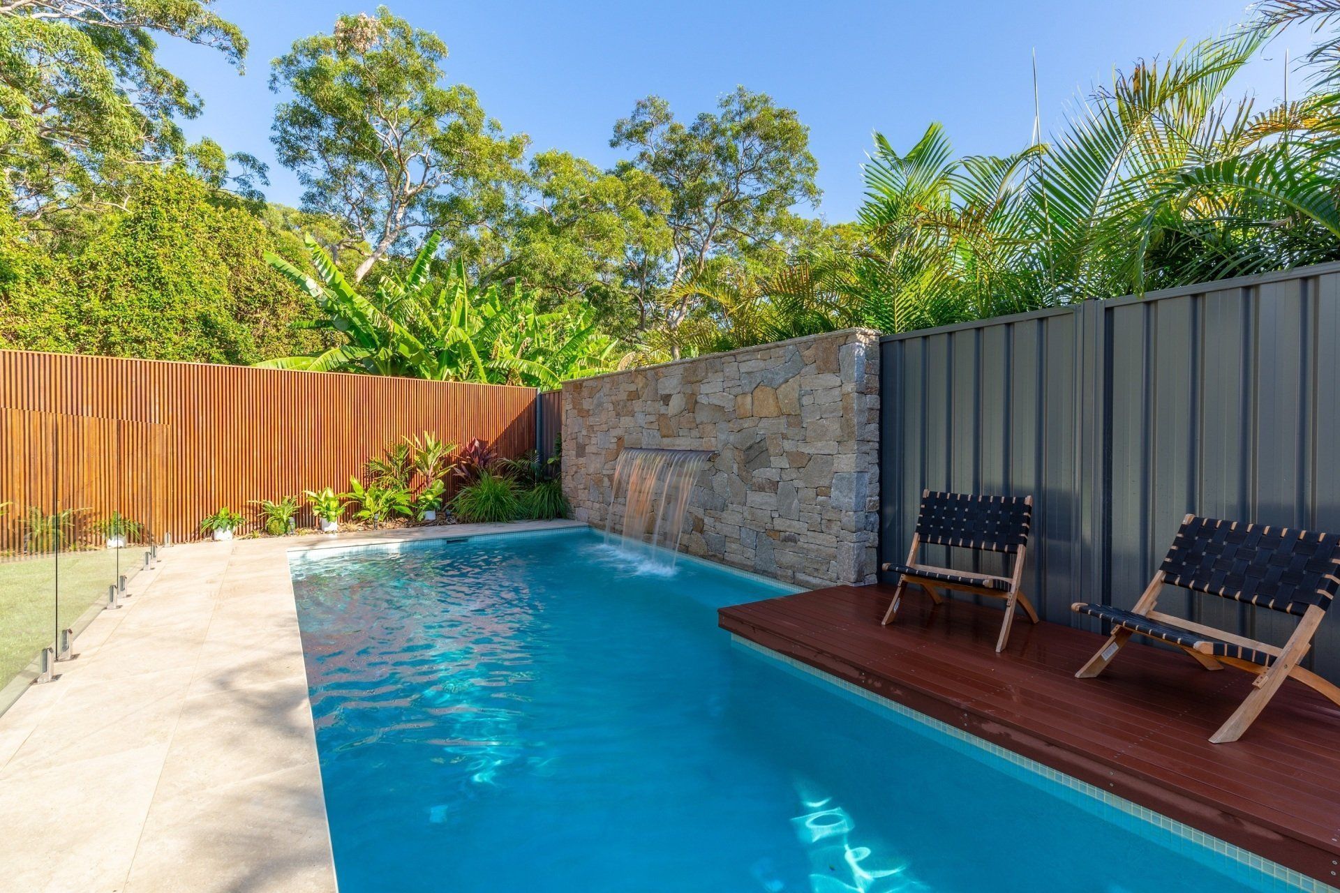 A large swimming pool surrounded by a wooden fence and chairs.