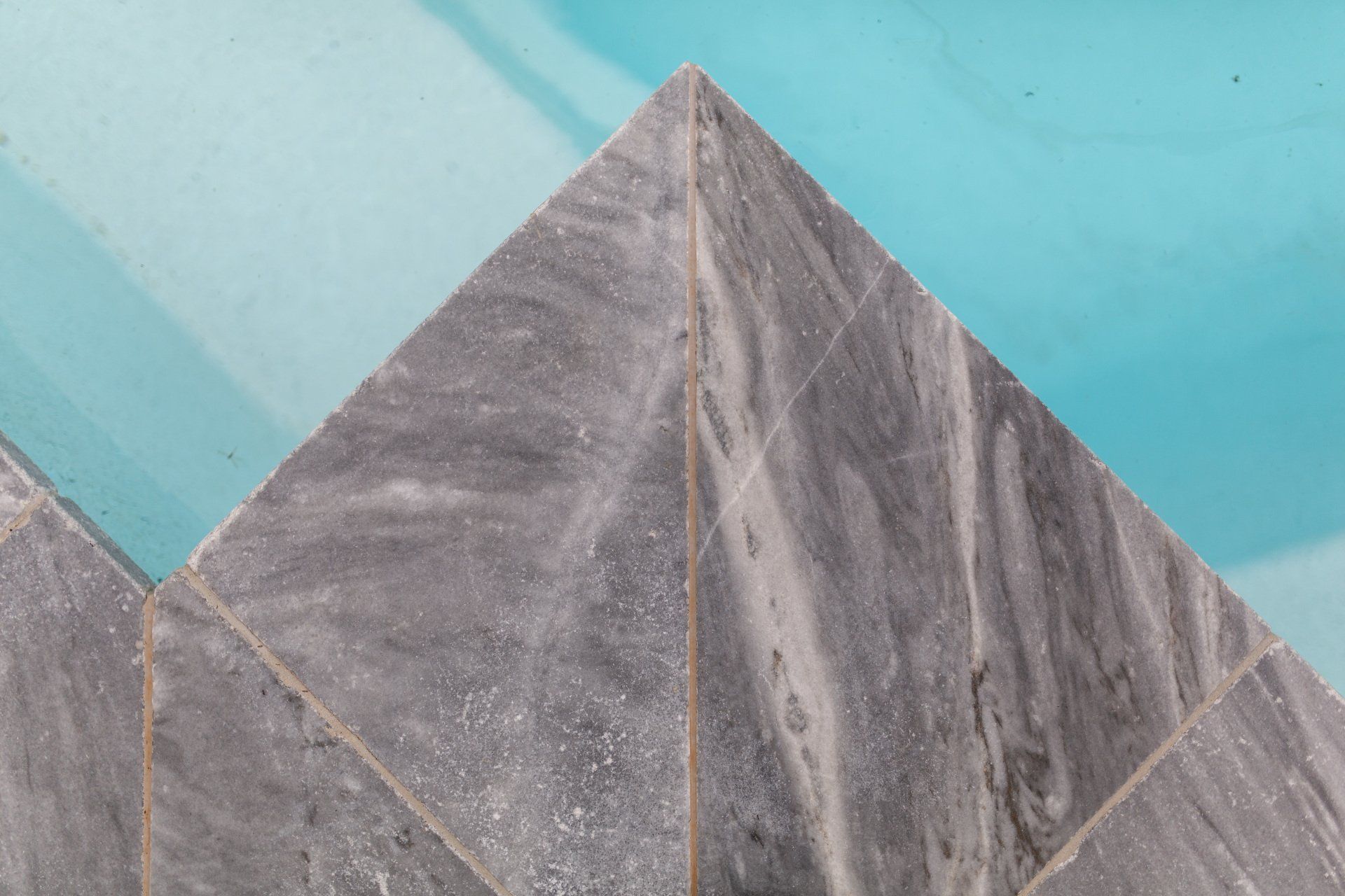 A close up of a marble tile floor next to a swimming pool.