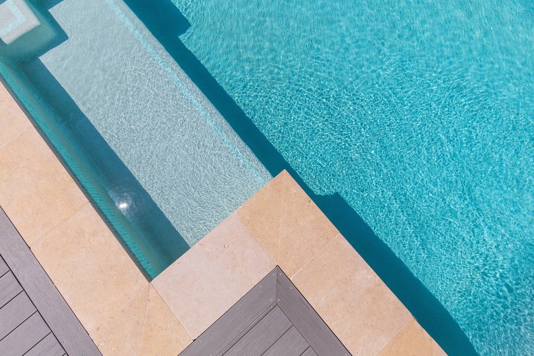 A swimming pool with a wooden deck and steps leading into it.