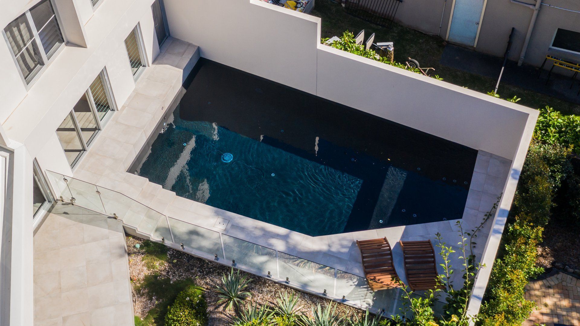 An aerial view of a large swimming pool in the backyard of a house.