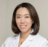 Smiling professional in a white coat against a light gray background