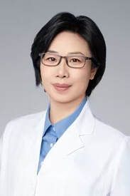 Portrait of a person in glasses and a white coat against a gray background