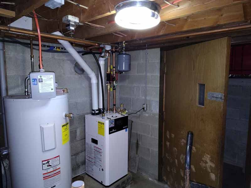 Basement utility room with furnace, water heater, and exposed pipes beneath a wooden ceiling.