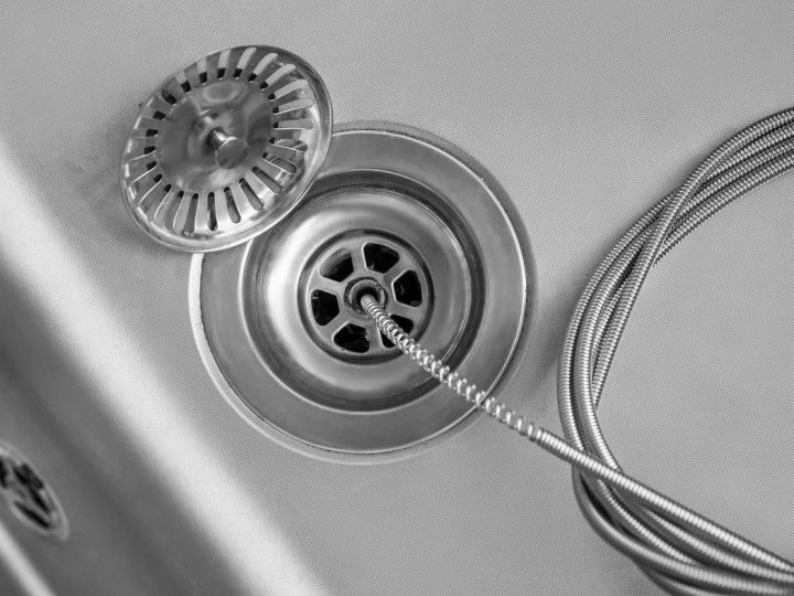 Stainless steel sink drain with a spray hose and strainer on a countertop