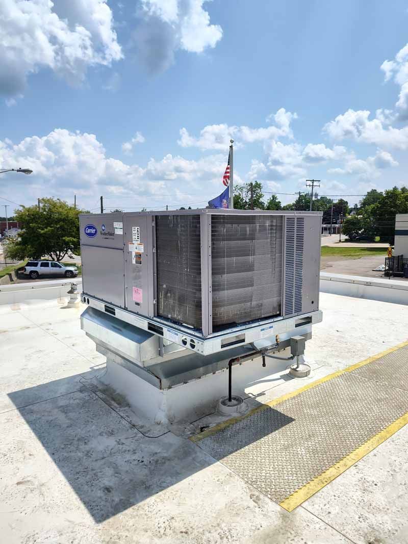 Large rooftop HVAC unit on a concrete pad under a partly cloudy sky.