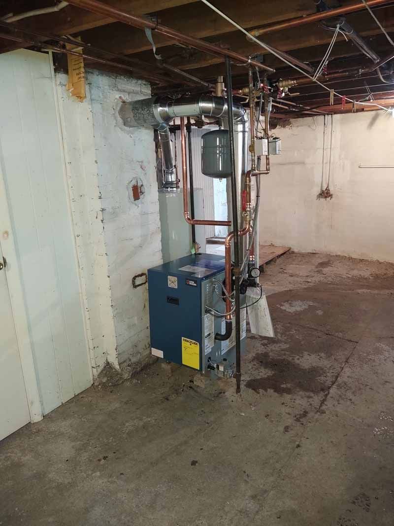 Partially finished basement with furnace, water heater, exposed ceiling, and concrete floor