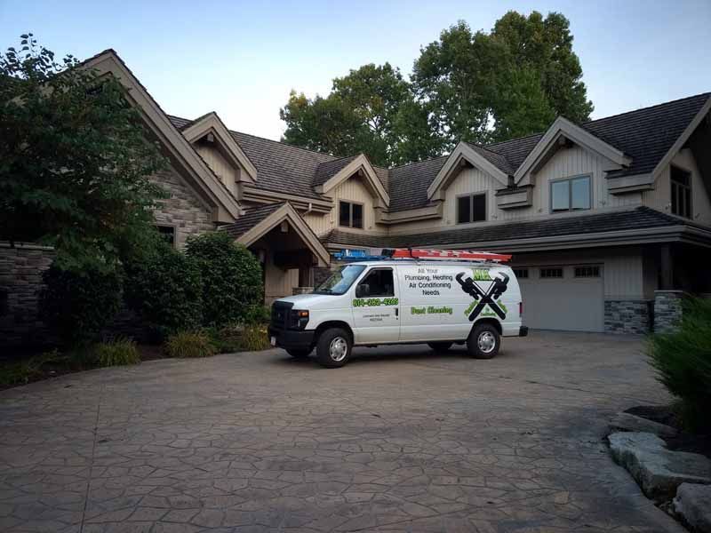 Moving truck parked in a driveway in front of a large house at dusk.