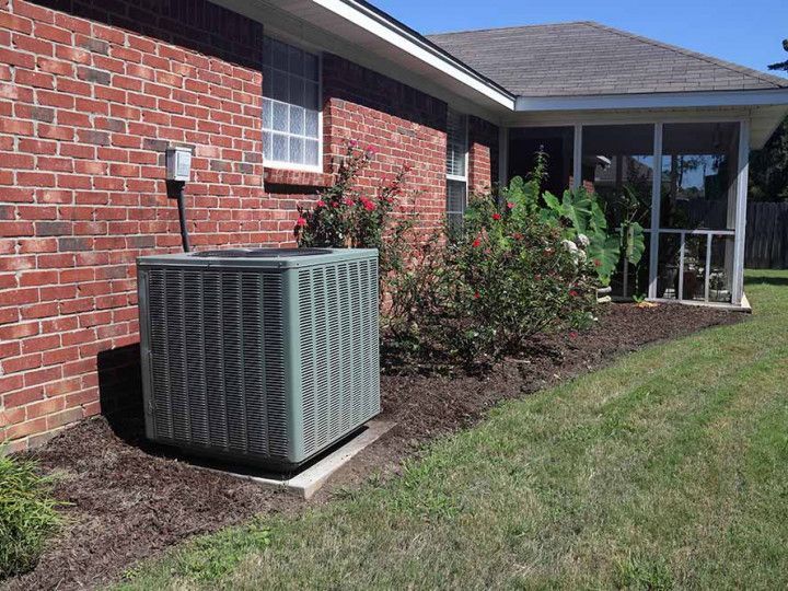 Outdoor HVAC unit beside a brick house near the lawn and patio entrance