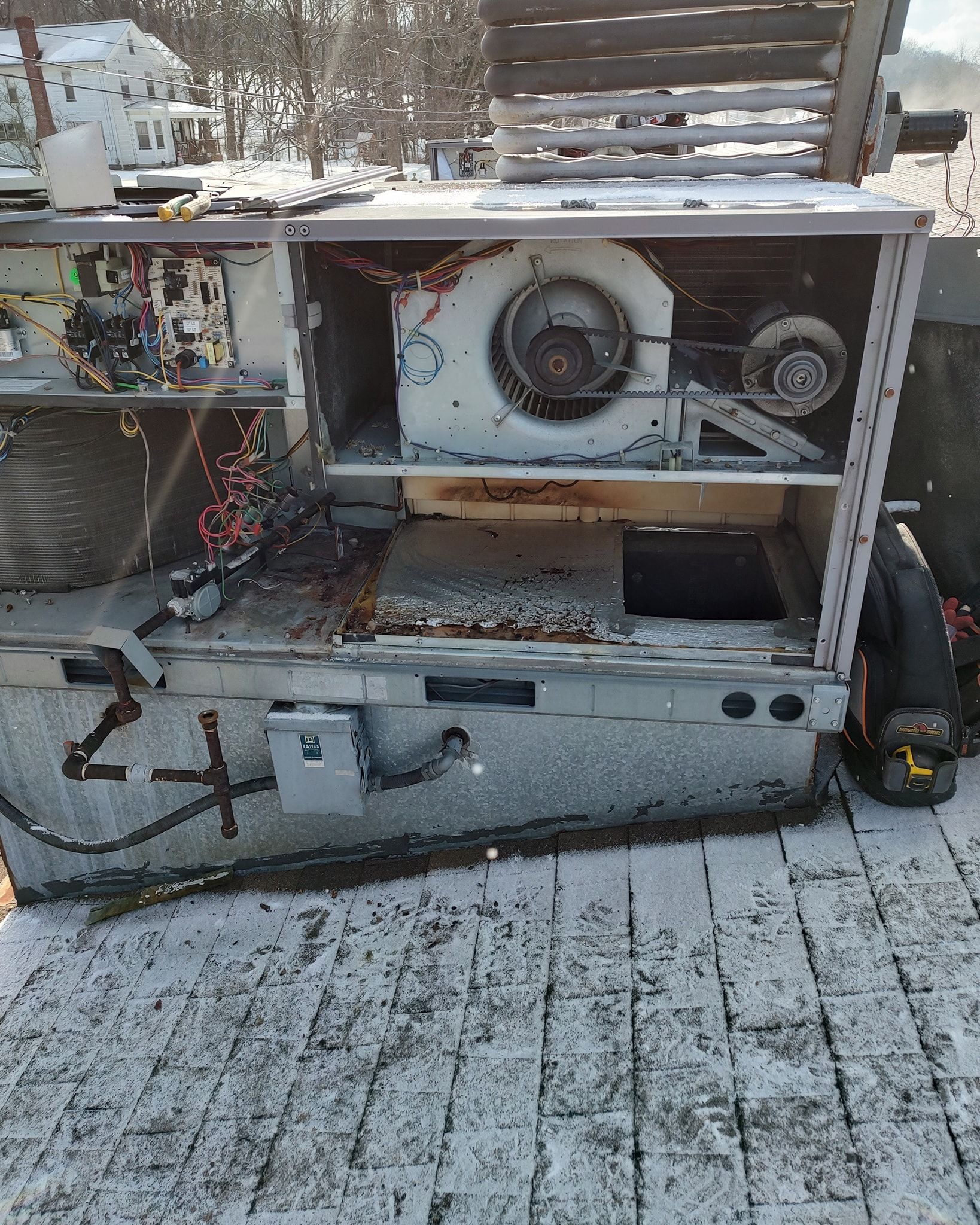 Snow-covered outdoor equipment with exposed gears and wires in a metal frame.