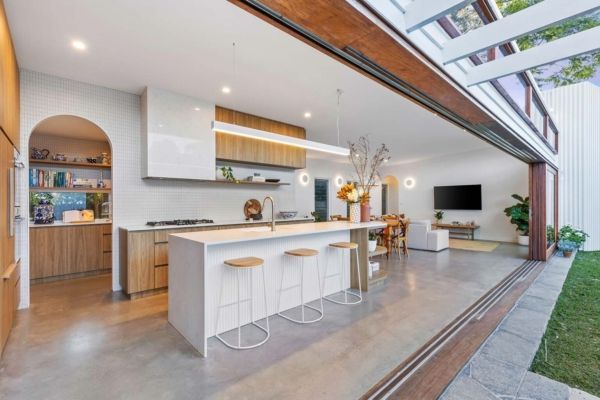 Modern kitchen with white island, wooden cabinets, and open to patio with grass — PK Kitchen Design in West Ipswich, QLD