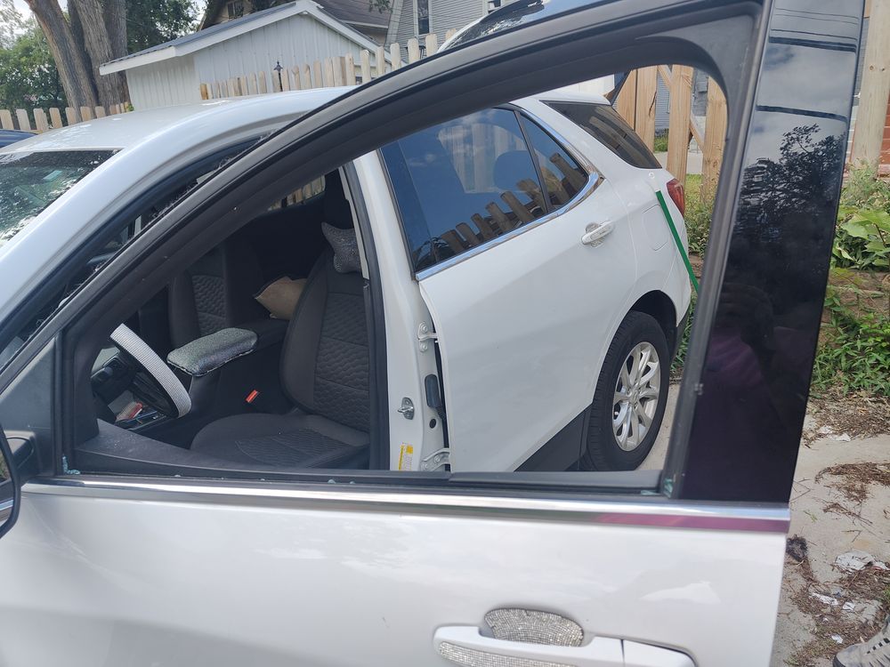 A white car with the door open is parked in front of a house.