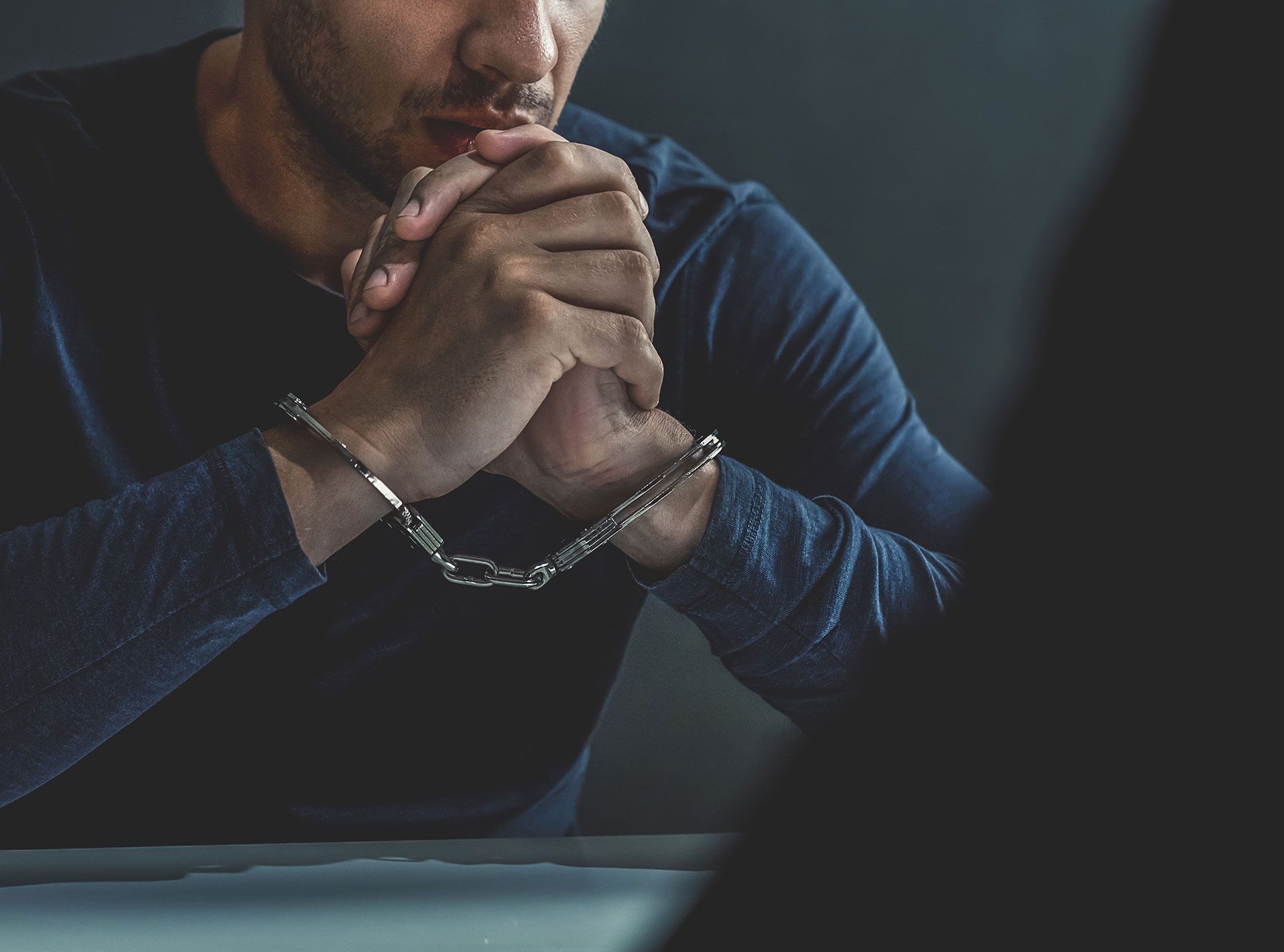 A man clasps his hands in handcuffs