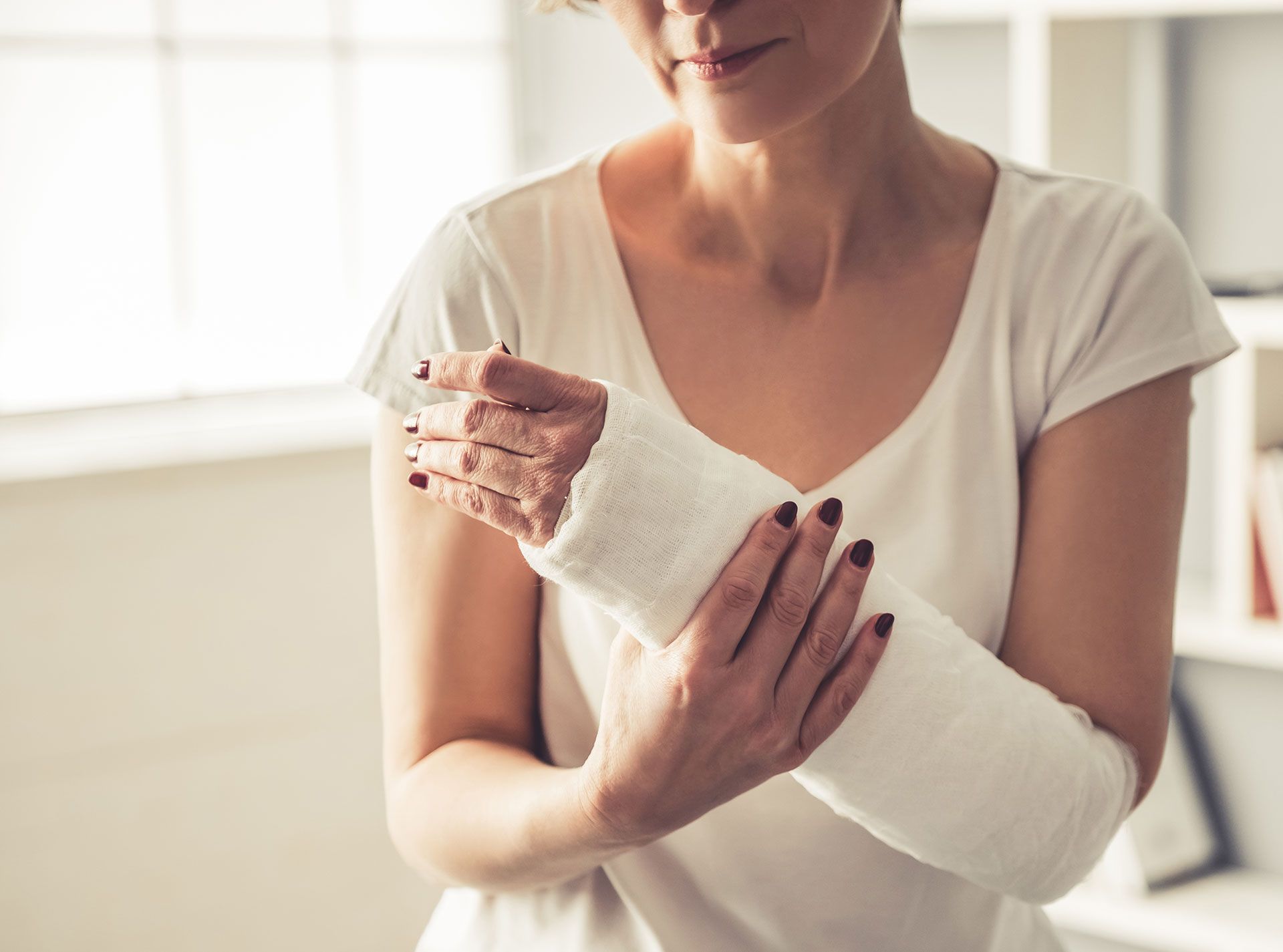 A woman holding her wrist in a white cast