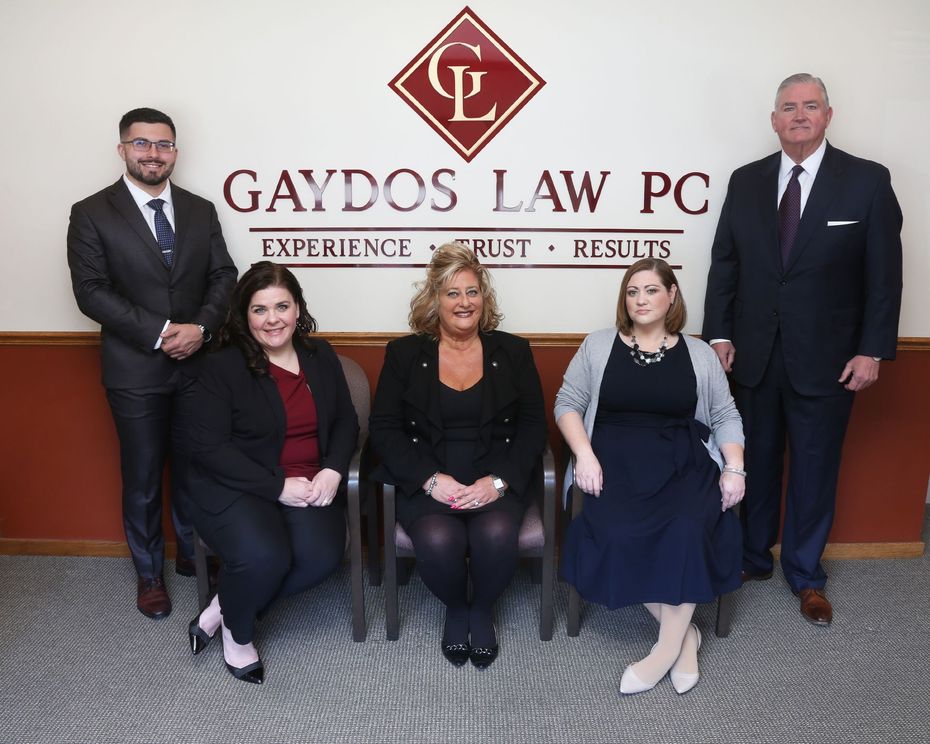 Group portrait of Gaydos Law PC team in front of the firm’s logo.