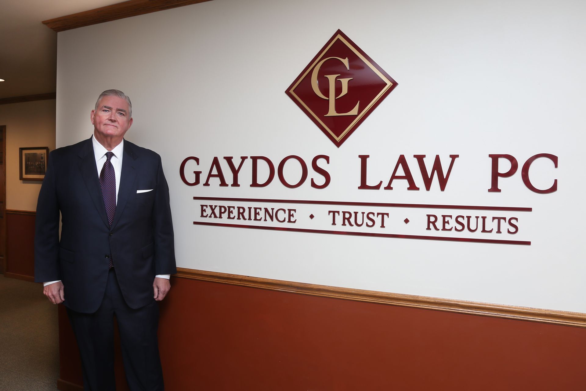 Joe Gaydos standing next to wall with the Gaydos Law, P.C. logo
