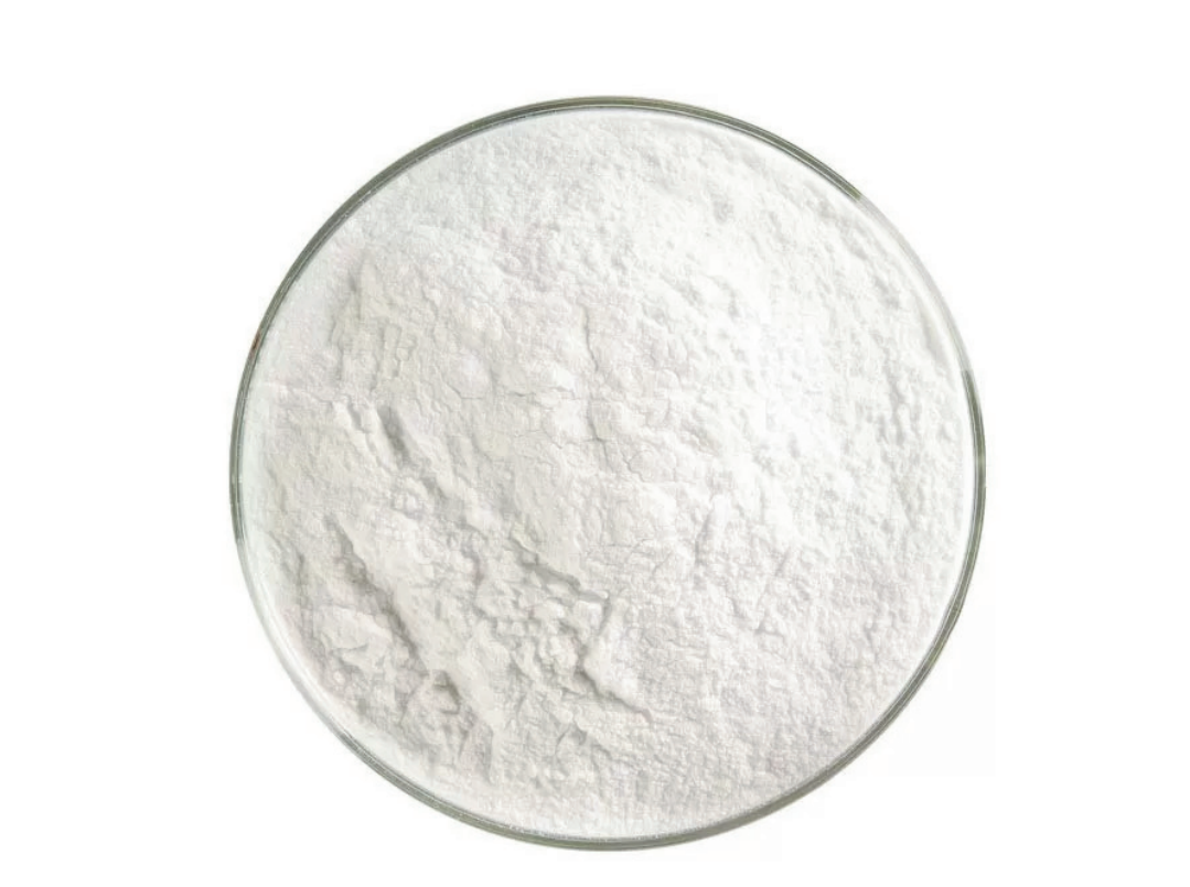 Uma tigela de vidro cheia de pó branco sobre um fundo branco.