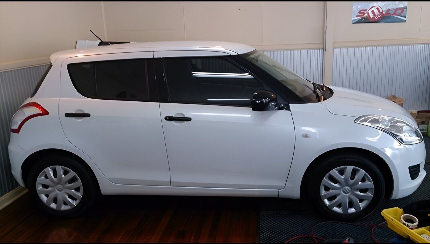 A White Car With A Red Arrow On The Side Is Parked In A Garage — Juz Tint In Batemans Bay, NSW
