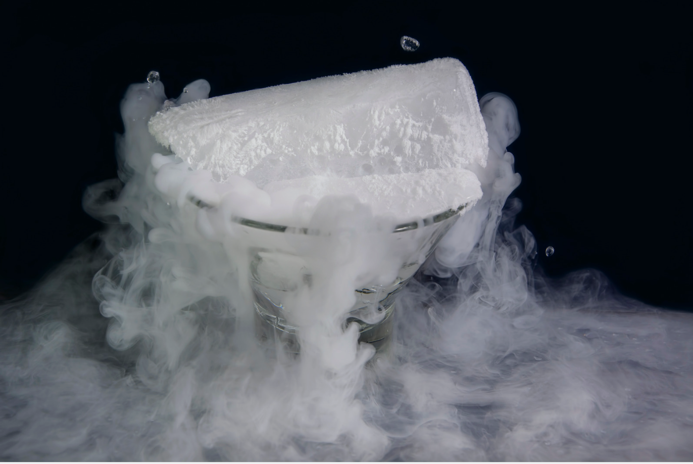 Ice block emitting white vapor against a dark background
