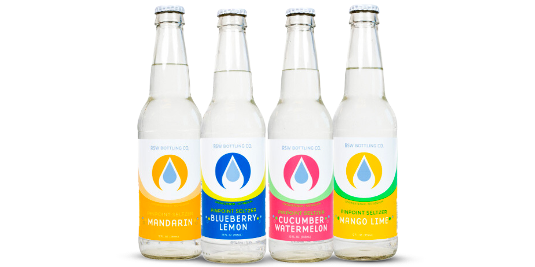 Four white beverage bottles with colorful labels lined up on a white background