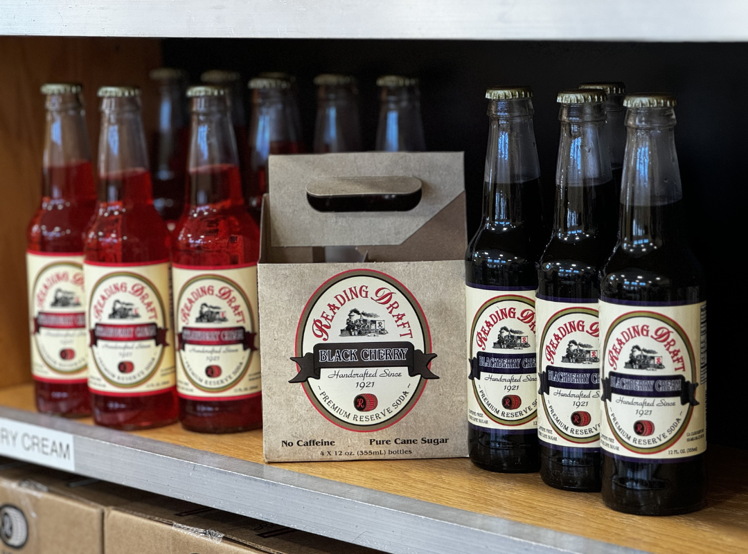 Row of bottled sauces and a boxed mix on a store shelf, with red and dark glass bottles.