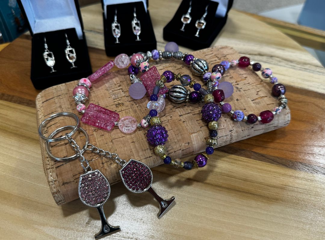 Handmade beaded jewelry set with pink, purple, and silver earrings, bracelets, and rings on a wooden surface