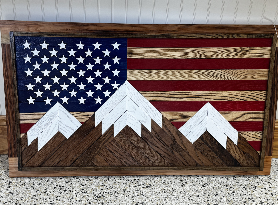 Wooden wall art of the American flag with three snow-capped mountains in front